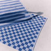 Two blue patterned beach towels on a light gray surface