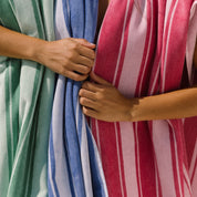 Close-up of hands holding multicolored striped beach towels.